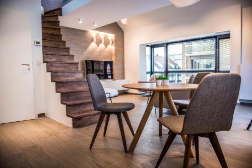 a dining room with a table and chairs and a staircase at Apart! & Moment! in De Haan