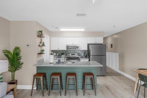 a kitchen with a counter with stools and a refrigerator at Newly Renovated Condo with Beach access steps away in Myrtle Beach