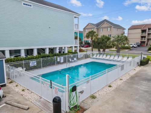 a swimming pool with a white fence next to a building at Newly Renovated Condo with Beach access steps away in Myrtle Beach