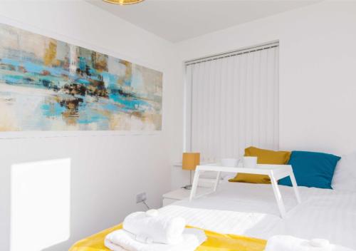 a white bedroom with a white bed and a painting at Levon House 2 Bed Apt with Netflix & Parking in Coventry in Longford
