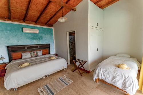 1 dormitorio con 2 camas y techo de madera en Hotel Boutique Noelani en Zorritos