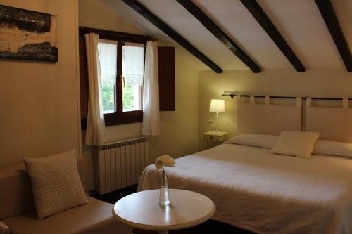 a bedroom with a bed and a table and a window at Casa Rural Ozollo in Gautegiz Arteaga