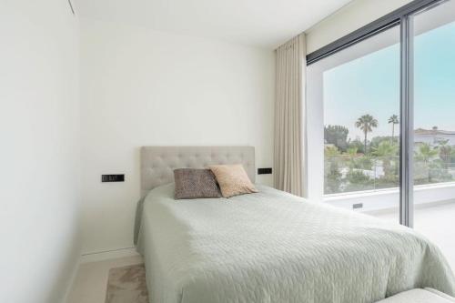 Dormitorio blanco con cama y ventana grande en Modern 4 Beds Luxe Villa 550m to Las Cañas Beach!, en Marbella