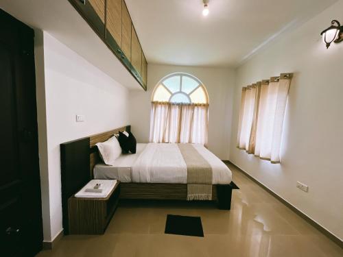 Schlafzimmer mit einem großen Bett und einem Fenster in der Unterkunft Hestia Chalet 3BHK Villa in Udagamandalam