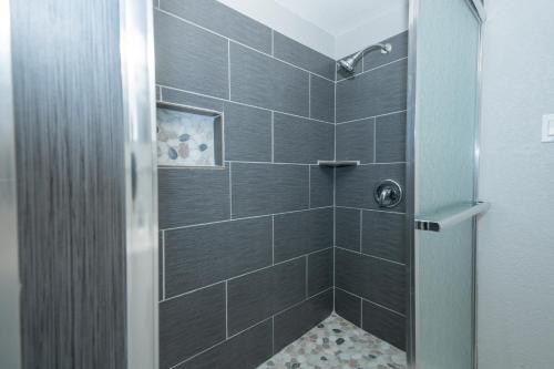 a bathroom with a shower with black tiles at Cultural Heritage Award winning home - Ideal for Holiday Stays & Lake Walks in Austin