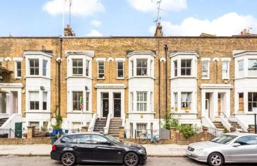 two cars parked in front of a large brick building at Charming bedroom in artist studio in London