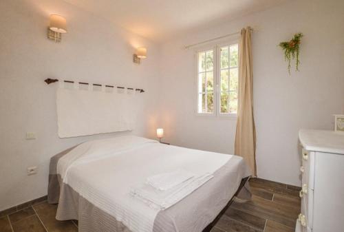 une chambre blanche avec un lit et une fenêtre dans l'établissement Villa Scandola, à Galéria