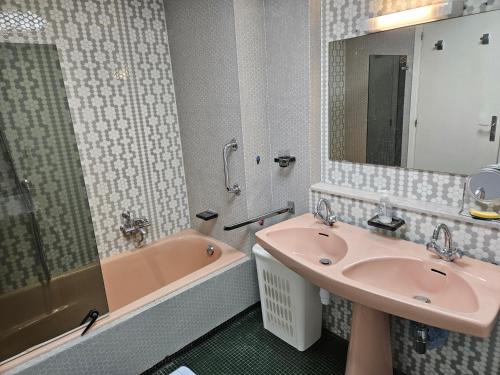 La salle de bains est pourvue d'un lavabo rose et d'une baignoire. dans l'établissement Juan les pins centre Le France grand 3P vue mer, à Antibes