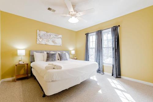 a bedroom with a large white bed with a ceiling fan at Breeze on Inn- Mins to Ft Jackson in Columbia