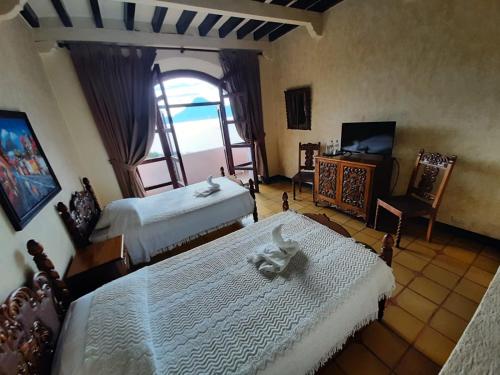 a bedroom with two beds and a tv and a window at Tzanjuyu Youth Resort in Panajachel