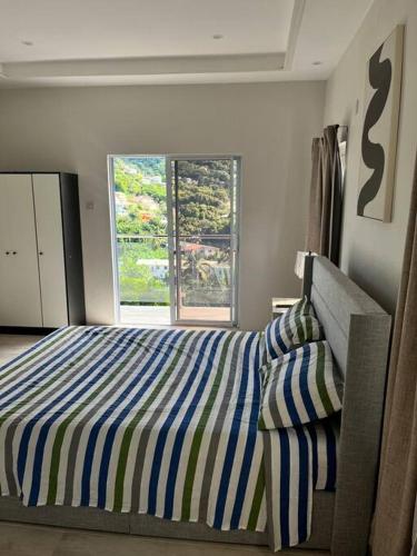 a bedroom with a striped bed and a window at Solaris 2: Peaceful Condo close to Tourist Spots in Corinthe