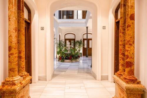 an internal corridor of a building with a hallway with plants at Coeo Apart-Hotel Fresca in Málaga