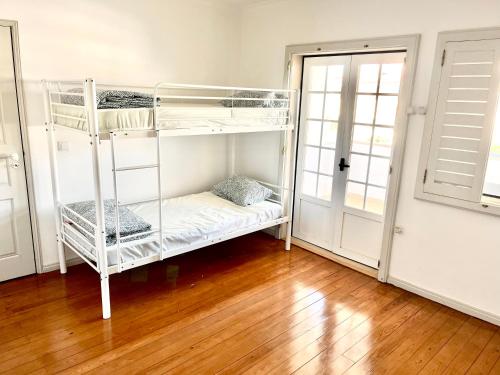 Ce lit superposé blanc se trouve dans un dortoir doté de parquet. dans l'établissement Carcavelos Summer Beach, à Carcavelos