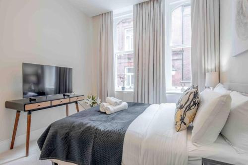 um quarto com uma cama, uma secretária e uma televisão em The Mayfair King em Londres