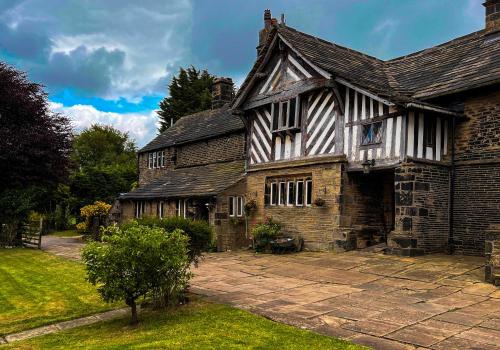an old stone house with a courtyard in front of it at New Hall, Elland in Elland