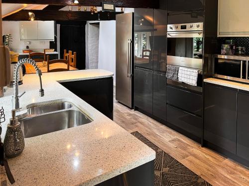 a kitchen with black cabinets and a sink at New Hall, Elland in Elland