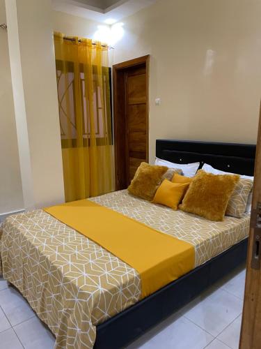 a bedroom with a large bed with yellow pillows at Charmante petite villa aux Mamelles in Ouakam