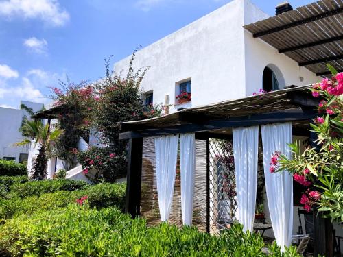une maison blanche avec des rideaux blancs dans la cour dans l'établissement Le Lanterne Resort, à Pantelleria