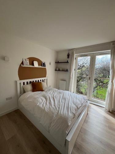 Un dormitorio blanco con una cama grande y una ventana en The Nest Tottenham - cosy one bed apartment, en Londres