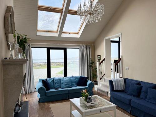 a living room with blue couches and a chandelier at Doleen House in Ballyconneely