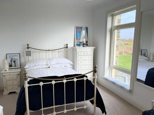 a bedroom with a bed with a dresser and a window at Doleen House in Ballyconneely