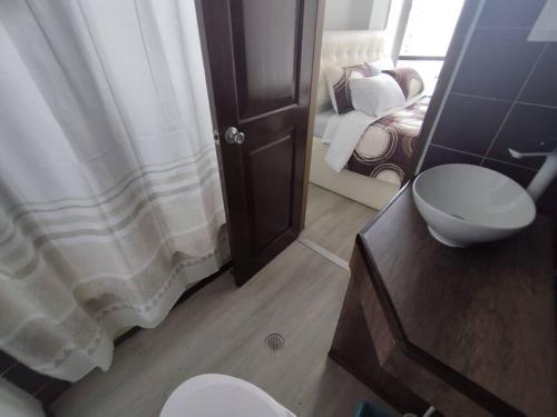 een badkamer met een wastafel, een toilet en een spiegel bij Hermosa Suite La Carolina in Quito