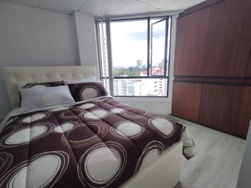 een slaapkamer met een groot bed en een groot raam bij Hermosa Suite La Carolina in Quito