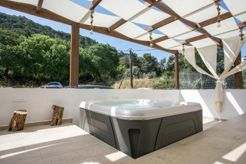 a hot tub on a patio with a pergola at La Vie Est Belle in Ixia