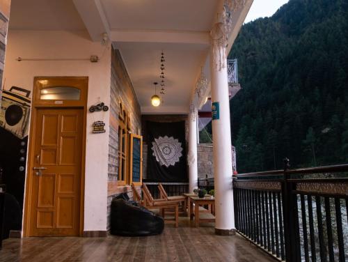 a balcony with a wooden door and a table and chairs at Wabi Sabi Riverside Hostel in Kasol