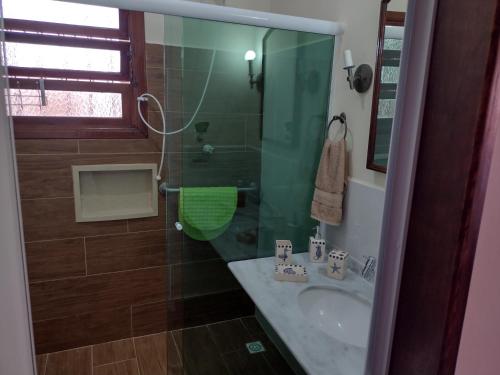 Un baño con lavabo y ducha de cristal. en Casa dos Prados, en Peruíbe