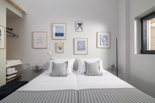 Una cama blanca en una habitación con cuadros en la pared. en Beachfront Salty Sea Luxury Suite 2 en Ágios Nikólaos