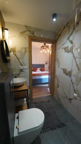 a bathroom with a toilet and a sink and a bed at Stara Plebania in Ponice