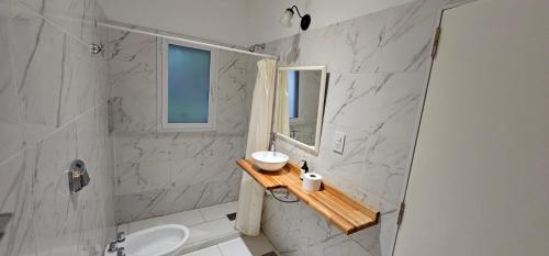Baño blanco con lavabo y espejo en Nuevo Hotel Parador en Roldán