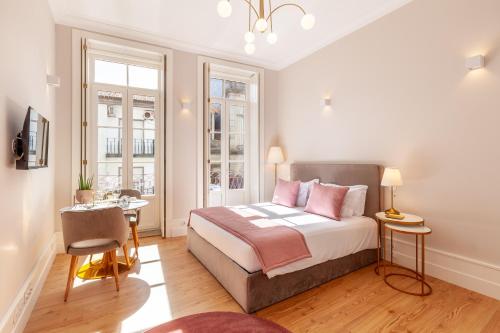 a bedroom with a bed and a desk and two windows at Living Valverde Studios - Minho's Guest in Braga