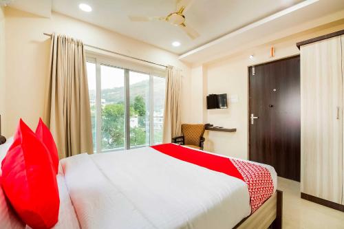 a bedroom with a bed with red pillows and a window at RR Towers by CJ in Vijayawāda
