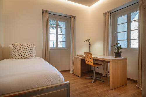 1 dormitorio con 1 cama, escritorio y ventanas en Casa Nª Srª das Graças, en Sintra