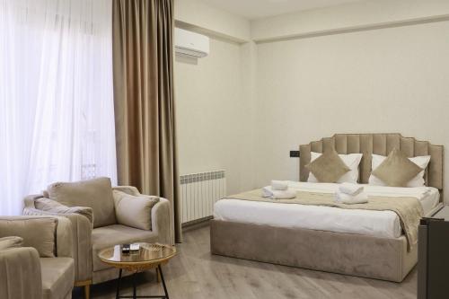 Royal Renaissance Hotel في يريفان: غرفة نوم بسرير واريكة وكرسي