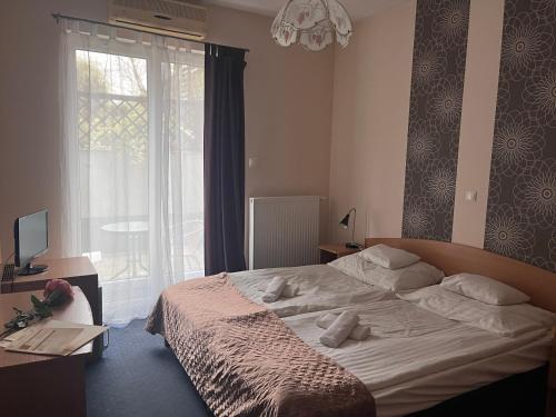 een slaapkamer met een bed en een groot raam bij Hotel Rose City in Boedapest