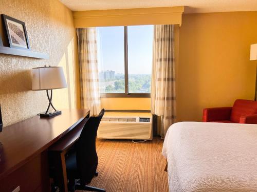a hotel room with a bed and a desk and a window at Courtyard by Marriott Alexandria Pentagon South in Alexandria