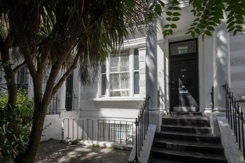 uma casa branca com escadas que levam à porta da frente em Portobello Road Artistic Studios 'BUDGET' em Londres