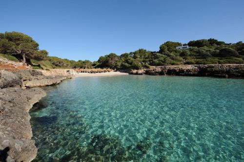 a beach with clear blue water and rocks at Rotonda Apartaments in Felanitx