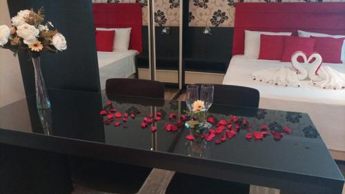 a room with a table with flowers and two beds at Hotel Guest in Venâncio Aires
