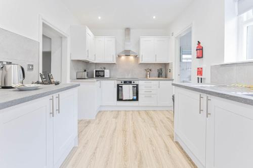 eine weiße Küche mit weißen Schränken und Holzböden in der Unterkunft Spacious 1 Bedroom Apartment in Cheltenham Centre 
