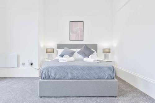 a white bedroom with a bed with two lamps at Spacious 1 Bedroom Apartment in Cheltenham Centre 