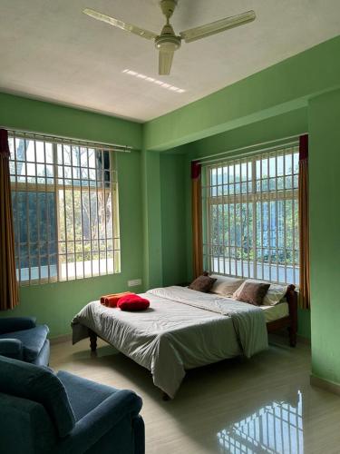 a green bedroom with a bed and two windows at Sana Riverside in Madikeri