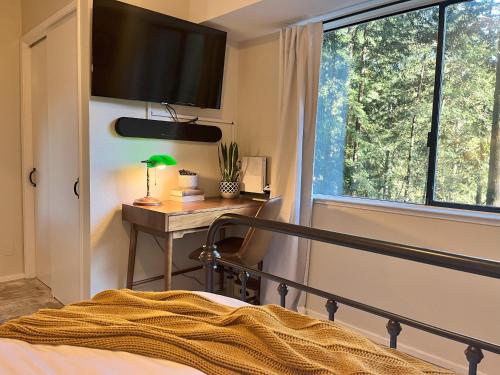 a bedroom with a bed and a desk and a window at Artist's Perch in Guerneville