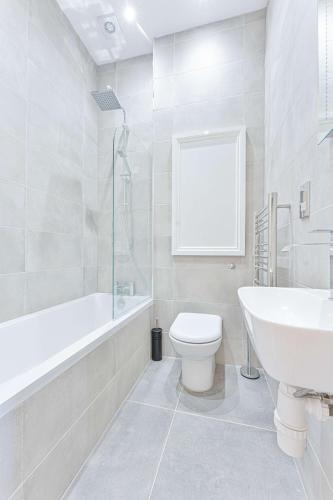 a white bathroom with a toilet and a sink at Stylish 2 Bedroom Apartment in Central Cheltenham in Cheltenham