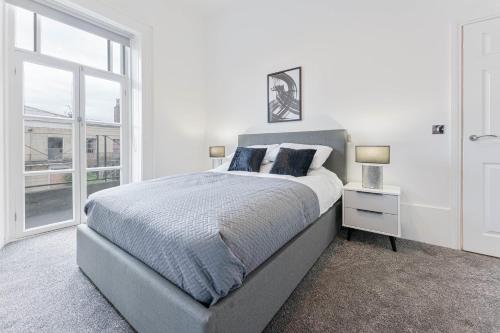 - une chambre blanche avec un grand lit et une fenêtre dans l'établissement Modern 2 Bedroom Apartment in Central Cheltenham, à Cheltenham