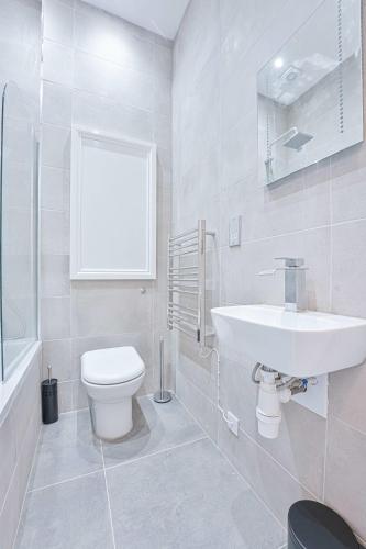 a white bathroom with a toilet and a sink at Stylish 2 Bedroom Apartment in Central Cheltenham in Cheltenham