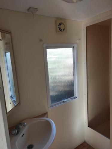 une salle de bain avec un lavabo et une fenêtre dans l'établissement Mobil-home dans un beau cadre à 15 km des plages., à Lunel
